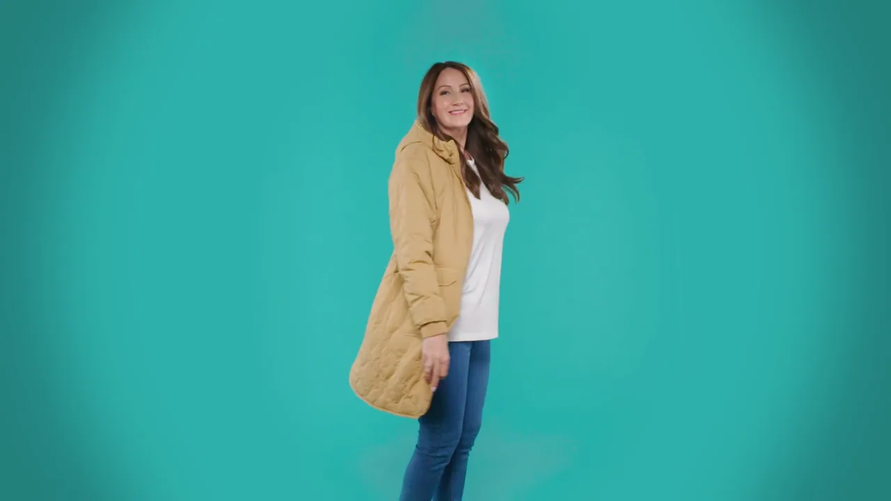 A model wearing a tan quilted coat against a teal backdrop in the Ideal World fashion film.